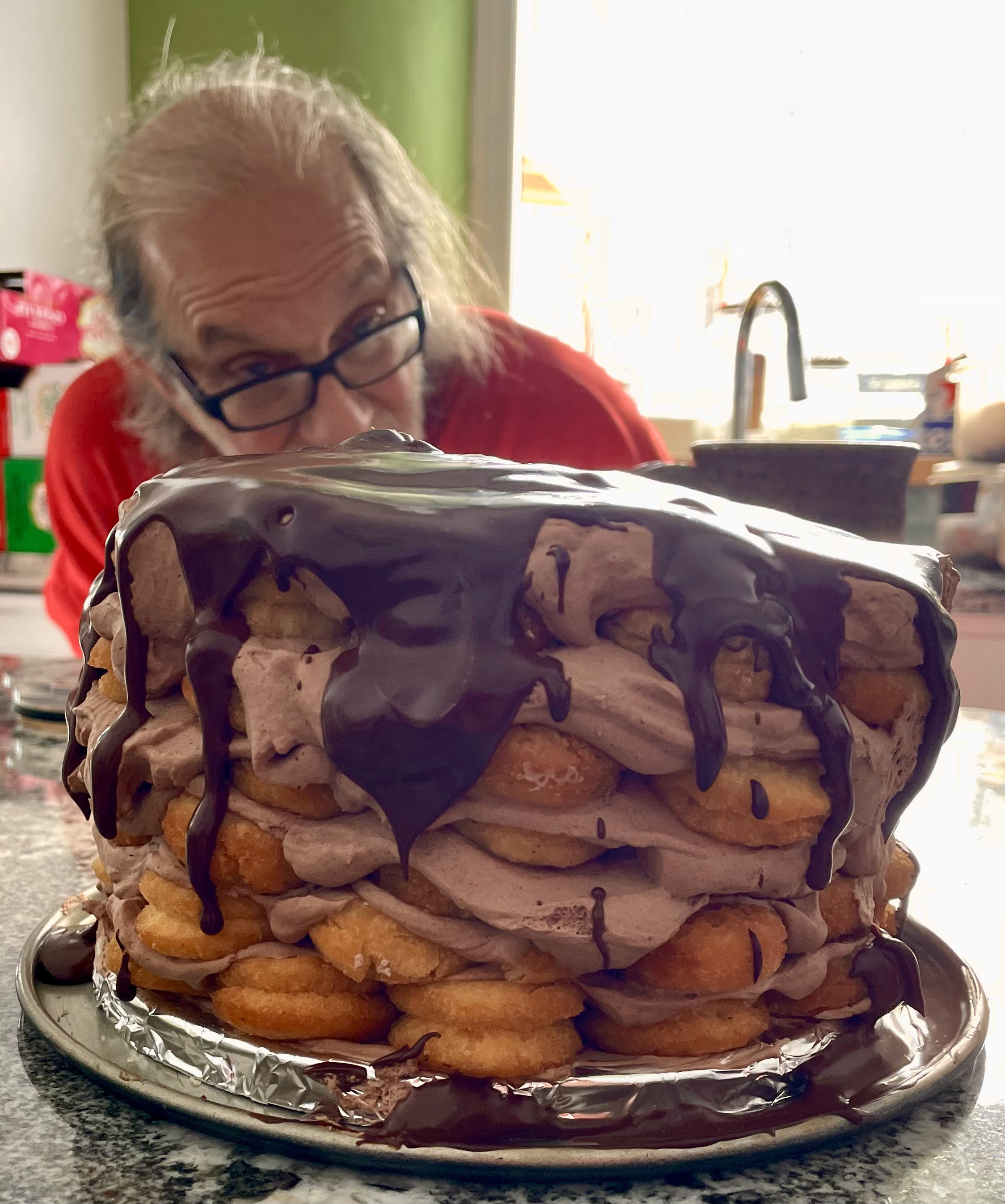 A donut cake made with fresh cake donuts and mocha whip cream and a chocolate coating.